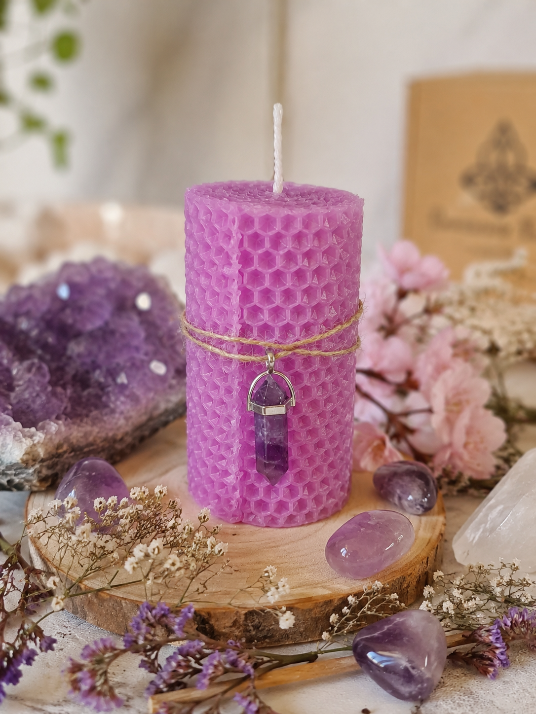 Bougie Améthyste Bio en cire naturelle violette avec pendentif en améthyste sur un décor zen.